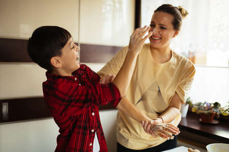 mom and son are cooking together in kitchen, preparing dough for cookies, happy family is stained in flour, joy. Laughter.の写真素材