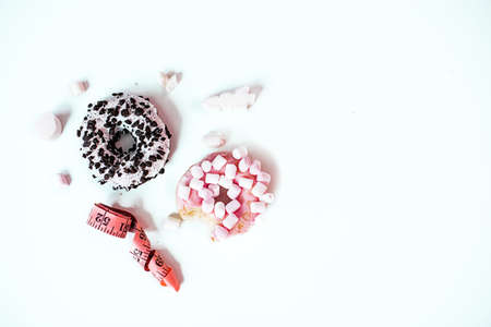 Sweet donut with marshmallow and Tape Measure on white background. Healthy lifestyle and diet concept. Flat lay, day lightの写真素材