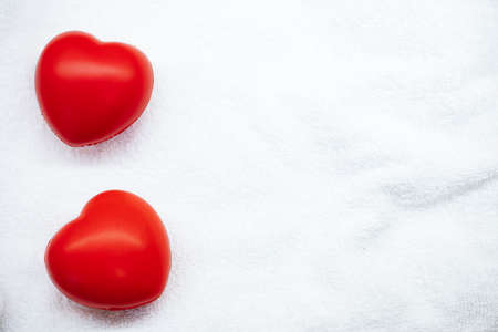 Two red hearts on white fluffy towel. Valentine's day. Love and romance. SPA salon. Gift certificate. Festive background. Body care. Beauty salon. Cosmetic procedures. Beauty and relaxation.の写真素材