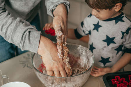 Photo of male hands, soiled in dough. Little boy, son admired Oversees process of making cookies at home. Dad and son. Teamwork. Happy people. Kitchen.の写真素材