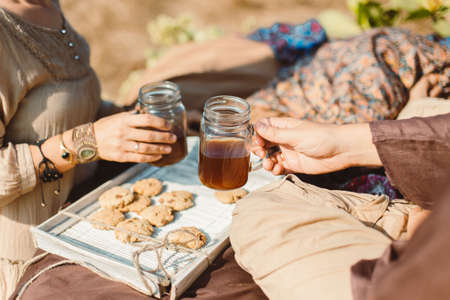 Picnic of couple in clothes made of natural materials, linen, beige, brown tones. Tea drinking, Indian culture, early morning. Meditation, relaxation. Unrecognizable personの写真素材