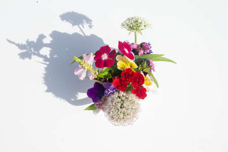 Vase with bouquet of colorful beautiful summer flowers, standing on white table. Sunlight, play of light and shadow. View from above.の写真素材