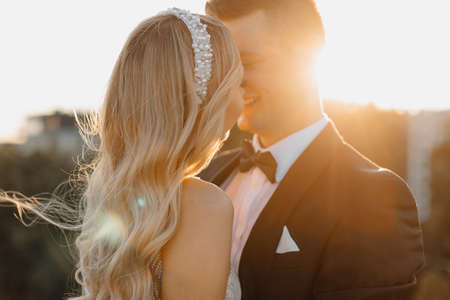 Romantic portrait close-up in rays of setting sun, gentle touch of bride and groom, happy together. hair flying in the wind. Expectation of happy life. wedding day.の写真素材