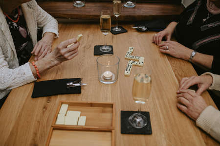 Hands of unrecognizable elderly people possibly women playing board games in cozy cafe outdoors...