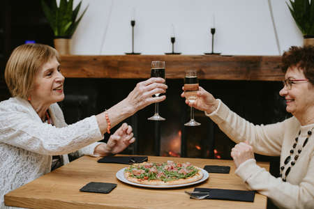 Smiling elderly dark-haired and fair-haired women with makeup dressed in black and white jackets...