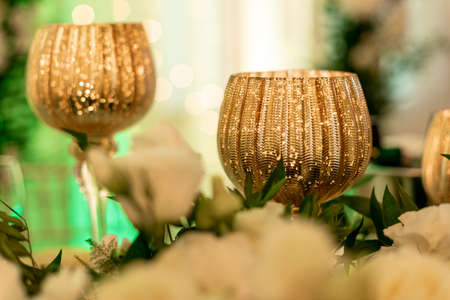 Luxurious gold wine glasses surrounded by white flowers are often decoration of table for newlyweds....