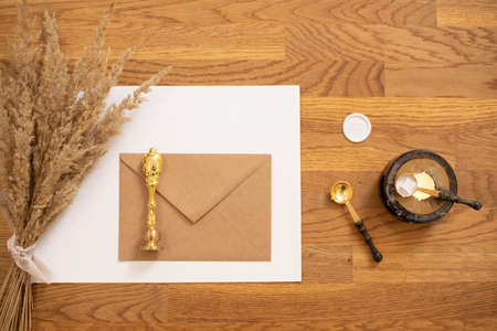 Flat lay photo composition greeting white paper envelope letter, decorating dry herb, seal wax, spoon, rubber, candleの写真素材