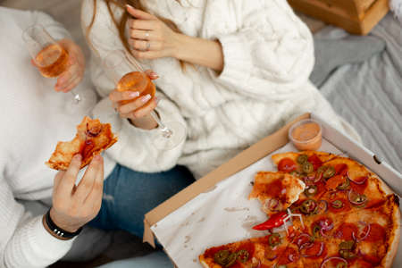 Delicious fragrant pizza and wine in glass glasses gives pleasure to couple in love on romantic date. Pleasure of eating. Excellent appetite. Delightful moments of life.の写真素材