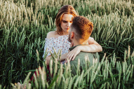 Young wife and husband walking at field, hug together. Girlfriend and boyfriend looking at each other spending time.の写真素材