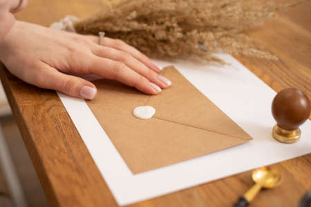 Cropped photo woman hand making greeting card paper envelope handmade, craft on wood desk, sealing...