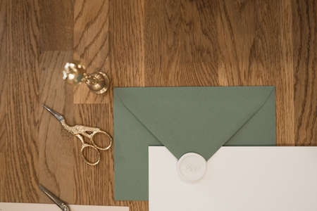 Top view of composition grey and white greeting invitation envelopes with white wax seal, golden scissors and stamp.の写真素材