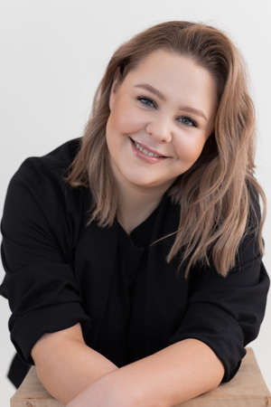 Vertical shot of smiling and friendly elegant blond woman in black clothes. Charming professional make up. Close upの写真素材