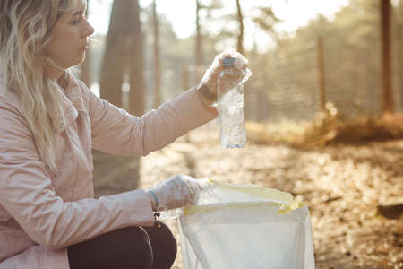 Sad woman volunteer and assistant clean forest from plastic waste bottle, rubbish. Recycling, pollution, eco sustainableの写真素材
