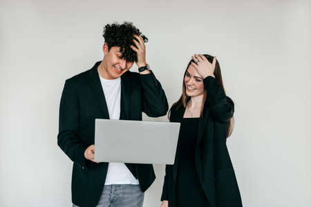 Two puzzled, surprised and shocked woman and man standing with laptop, looking at screen. Troubles in work, unbelievableの写真素材