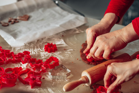 Close-up photo of hands. Man and woman cut out dough cookies. Christmas pastries, cozy kitchen,...