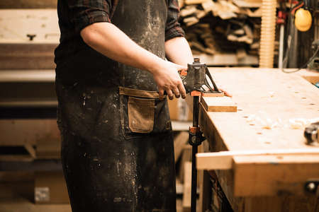 Unrecognizable cropped man, carpenter worker cutting plank with band saw electric plane on work...
