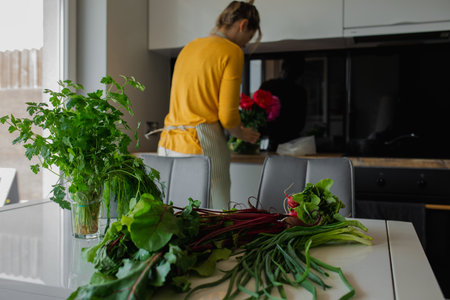 Healthy fresh beetroot vegetables with leaves on the table in light kitchen. Rearview of female...