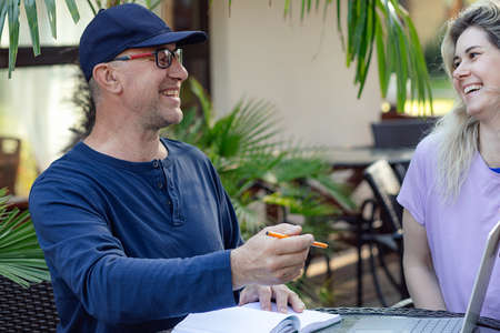 Portrait of happy family. Middle-aged man sitting at table with laptop in cafe, holding pen,...