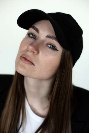 Portrait closeup of gorgeous young girl, studio background, copy space. Female casual black blazer and cap, trendy clothes and headdresses. Monochromatic collection of fashionable clothing for womenの写真素材
