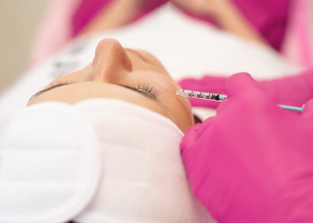 Close-up of young woman getting rejuvenation beauty injection into skin under eyes for modification of facial contour.の写真素材