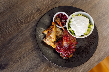 Roasted duck meat with green vegetable cabbage salad with white cream and berry sauce on black plate. Keto, paleo dietの写真素材