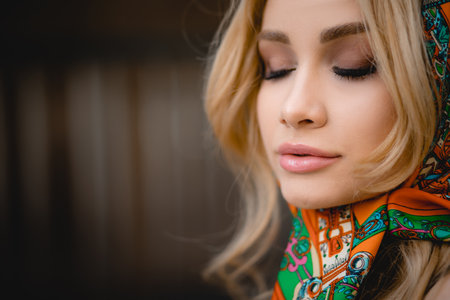 Close-up portrait of beautiful young blonde woman with closed eyes in headscarf, sensuality, make up