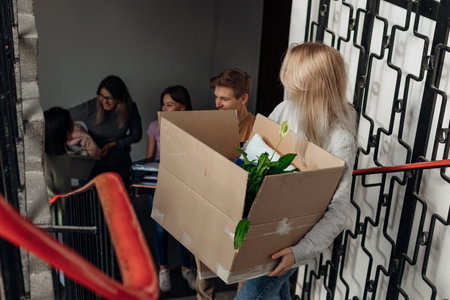 Smiling happy student friends move in accommodation, hold and carrying cardboard boxes on stairs. New rent for tenantsの写真素材