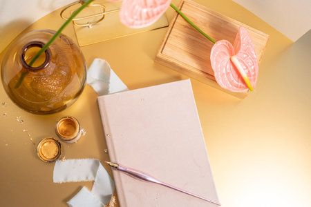 Composition of pink diary with fountain pen, writing ink and vase with spathiphyllum, peace lily flower on wooden boxesの写真素材
