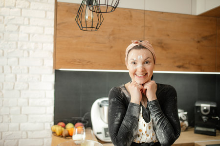 Happy woman cook in kitchen. Joyful lady get dirty in white flour for baking. Have fun in beautiful modern kitchen.の写真素材