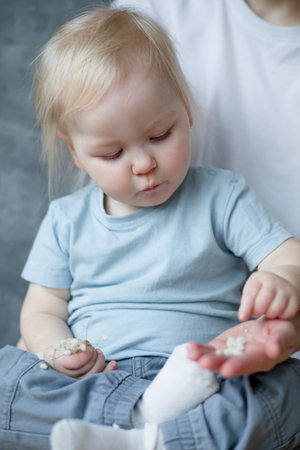 Close-up portrait of focused charming little girl sorting through small flowers from her mothers...