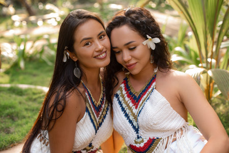 Closeup smiling pretty, attractive long haired women in dress with flower in hair pose in green jungles among palm treesの写真素材