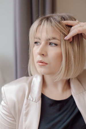 Portrait of charming blue-eyed blonde looking thoughtfully out window. Woman entrepreneur. Professional activity.の写真素材