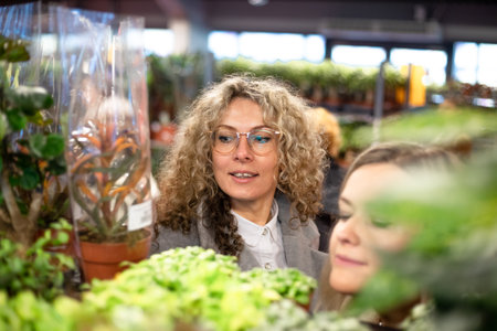 World of plants. Beautiful portrait of two charming women among green plants in garden center. Successful purchase.の写真素材