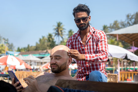 Portrait of man in jeans and sunglasses doing massage colleague surfing internet summertime during...