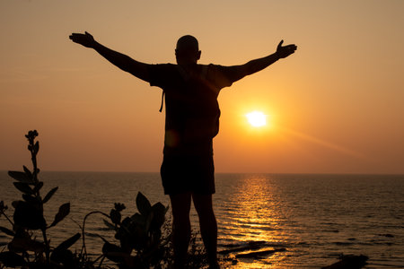 Man stand with arms wide open on beach and look at water. Traveler spend past day close to waves,...