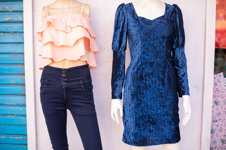 Two female mannequins dressed in dress and jeans with blouse hang on wall of shopping pavilion at flea market. Private business. Retail trade. Sale of womens clothing.の写真素材