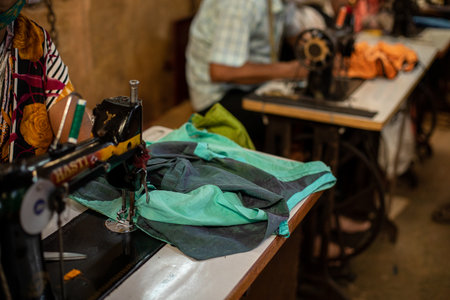 Goa, India, February 2023. Close-up of old sewing machine stitching green fabric clothes put...