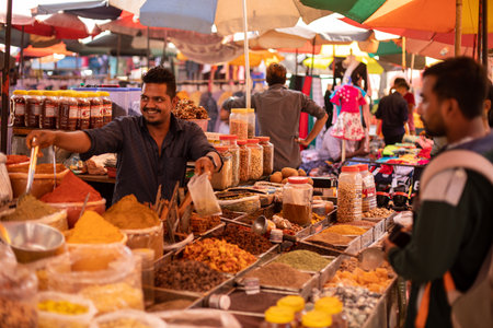 Goa, India, February 2023. Portrait of young smiling Indian man standing at stall in local market, selling spices.のeditorial素材