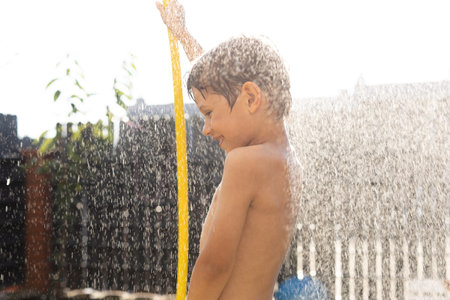 Homemade fountain was made by boy from watering hose on sunny summer day in backyard of house.
