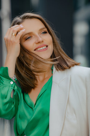 Modern business women. Charming smiling businesswoman in white business jacket with stylish hairstyle on summer day.の写真素材