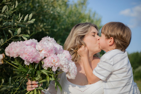 Family love, care. Boy, son in T-shirt hugs, kisses his mother, congratulates her on holiday.の写真素材
