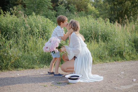 Love for parents. Little son hugs and kisses his mother on summer on rural road.Family relations.の写真素材