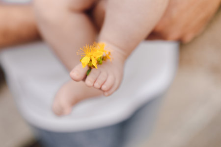 Focus is on baby s foot with tiny fingers with yellow flower inserted. Child protection. Baby care.