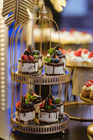 Cakes similar to small cakes , decorated with fresh berries stand at wedding event, party, holiday.の写真素材