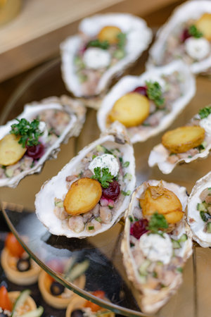 Close-up of cooked oysters with sauce, herbs and cucumber in separate sink on glass tray. Seafood.の写真素材