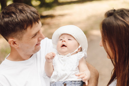 Happy parents with their baby on summer day forwalk in park. Protection, protection of childhood.の写真素材