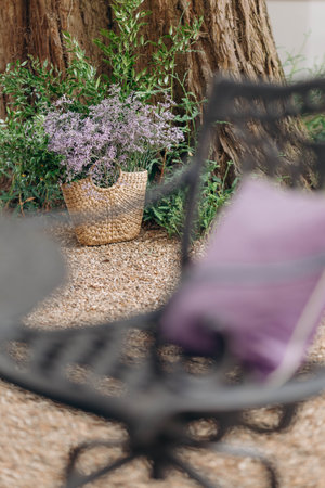 Image focuses on wicker basket with armful of lilac flowers standing by trunk of old tree.の写真素材
