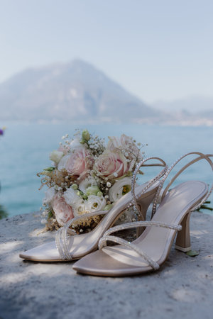 Close-up of open wedding shoes with rhinestones and delicate bouquet of bride lie on summer outside.の写真素材