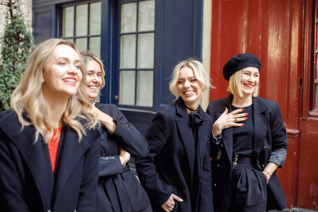Four charming female friends enjoy socializing, walking, on spring day in city.の写真素材