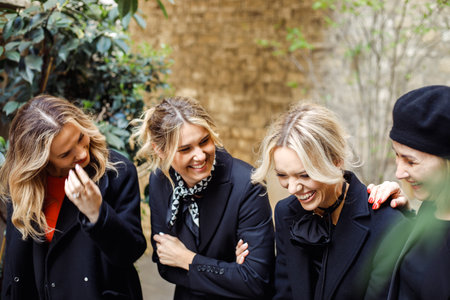 Positive emotions. Four charming female friends enjoy socializing , talking on spring day in city.